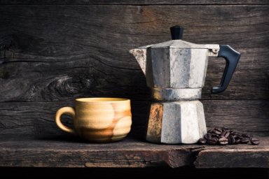 Nostalgischer Espressokocher mit Kaffeebohnen und einer Kaffeetasse