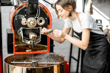 Junge Frau riecht an aromatisierten gerösteten Kaffeebohnen