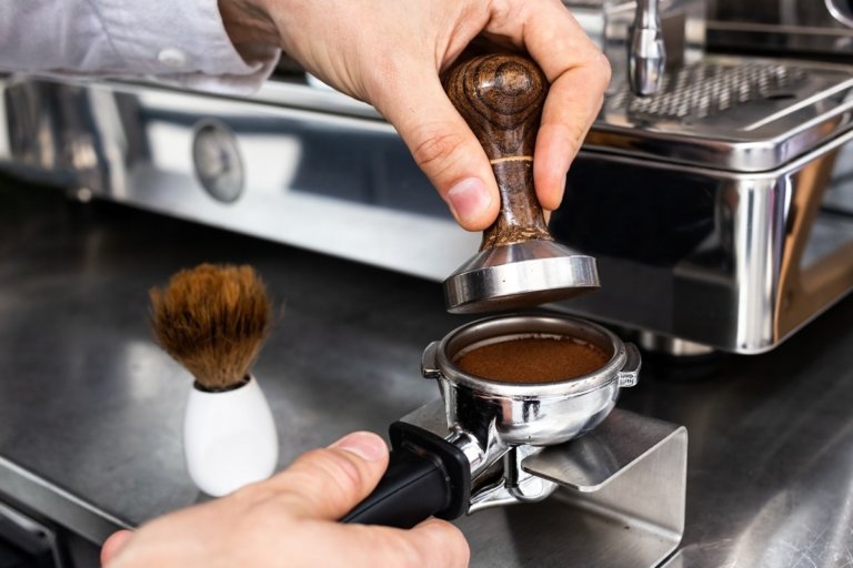Tamper komprimiert Kaffeepulver in einem Siebträger