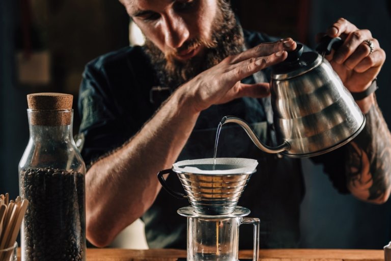 Mann übergießt Kaffeefilter mit heißem Wasser