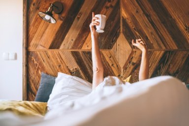 Frau im Bett mit Kaffeetasse