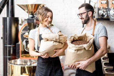 Eine Frau und ein Mann halten Säcke mit Kaffeebohnen 