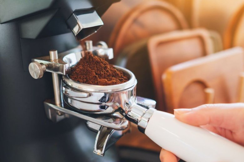 Espressomühle mahlt Kaffeepulver in einen Siebträger