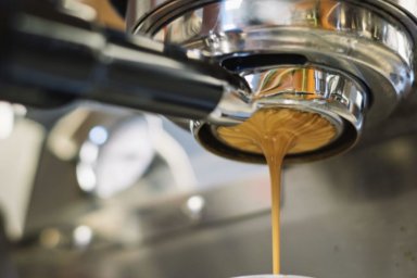 Frisch gebrühter Espresso, der vom Siebträger in die Tasse fließt